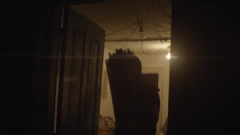 A Man Carries Bundles Of Sticks Through A Doorway