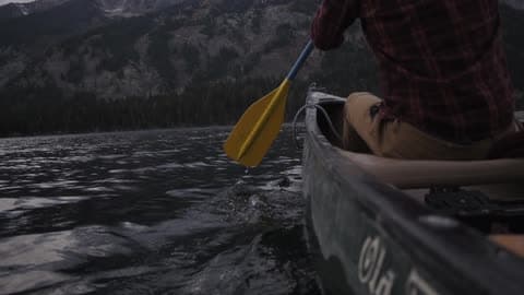 A Man Paddles In A Kayak On A Lake