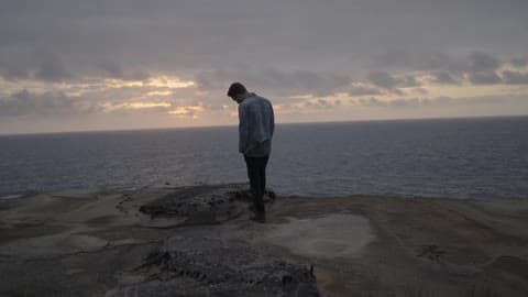 A Man Stands On A Beach On An Overcast Day