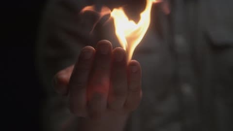 A Person Holding A Flame In Their Hand