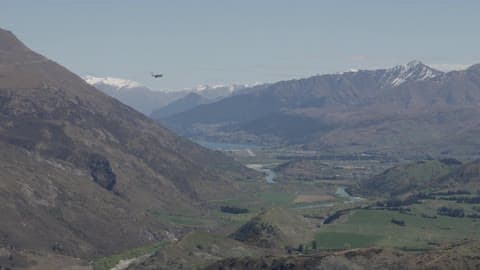 A Plane Flying Beside A Mountain In A Valley