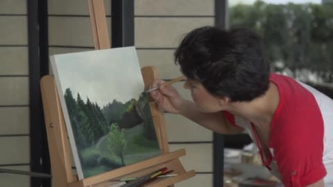 A Short Haired Woman Painting A Nature Scene