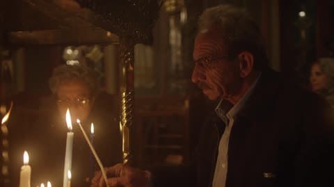 An Elderly Couple Light Candles In A Church