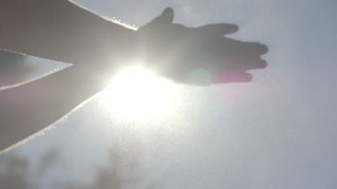 An Outstretched Hand With The Sun Glaring Behind It Before The Person Stretches Out The Other Arm And Wipes Something Off Their Hands
