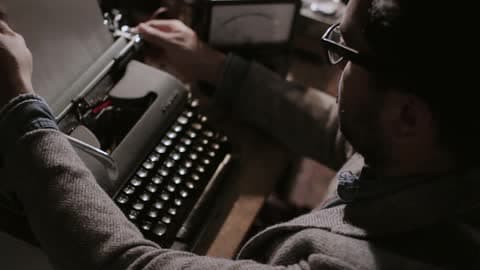 Man Loads A Piece Of Paper Into A Typewriter