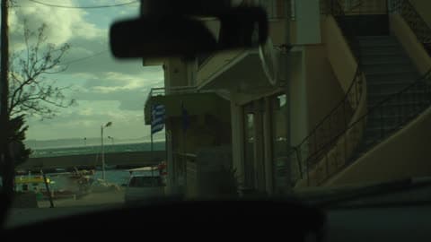 Person Driving Down A Road By The Water On A Cloudy Day